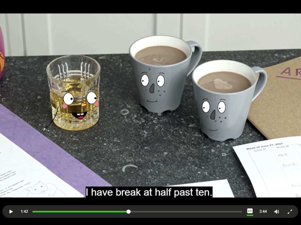 A still from a video showing a glass of juice and two mugs of coffee with cartoon eyes placed on a desk above the subtitles 'I have a break at half past ten'