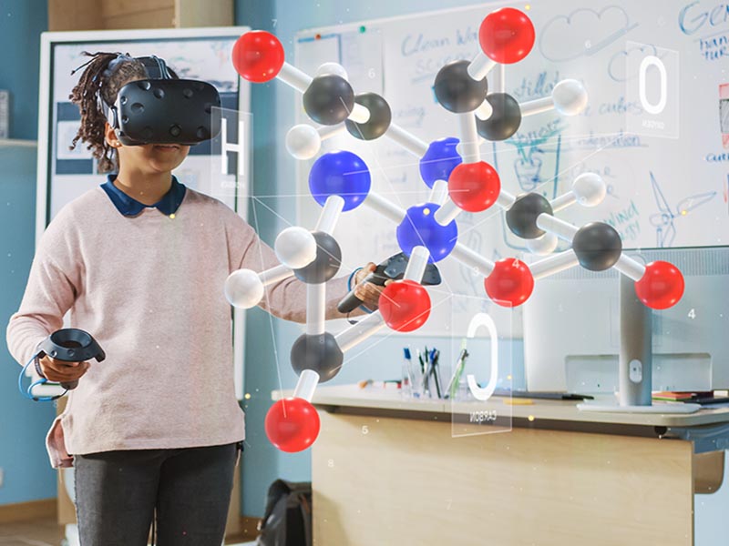 A student wearing a virtual reality headset in a classroom with a 3D molecular structure superimposed in front of them